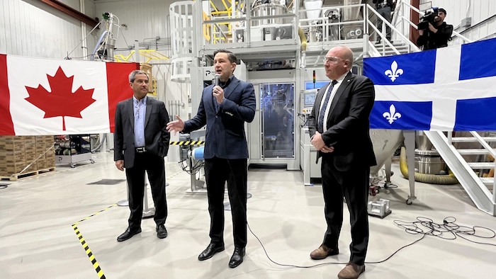 Pierre Poilievre parle au micro devant des drapeaux canadien et québécois.