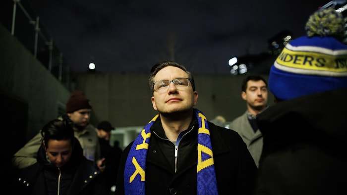 Pierre Poilievre portant un foulard aux couleurs de l'Ukraine, dans une foule.
