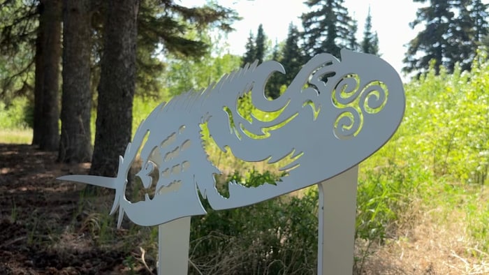 Une pierre tombale en métal en forme de plume à l'intérieur de laquelle une main et un aigle ont été gravés.