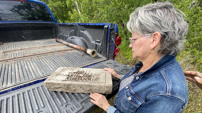 Une femme qui regarde une plaque funéraire.