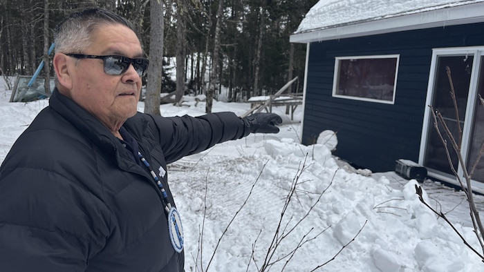 Jean-Chatles Piétacho pointant du doigt une fenêtre d'un chalet.