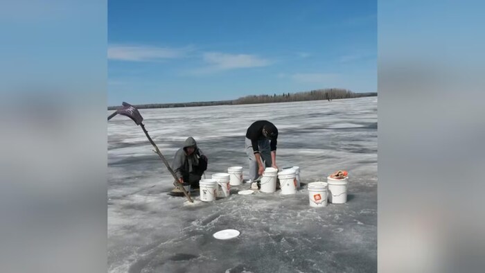 Deux hommes mettent de l'eau dans des seaux.