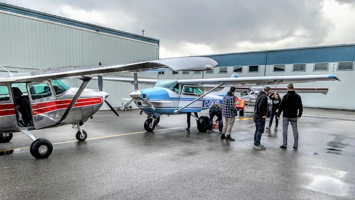 Un groupe de personnes charge des biens de première nécessité dans deux avions légers.