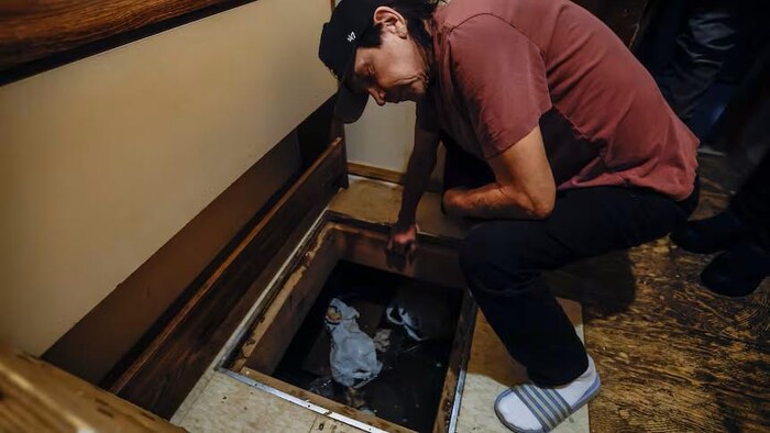 Murray Trout est penché au-dessus d'une ouverture sur le vide sanitaire, à Pimicikamak le 7 janvier 2026.