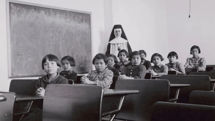 Niños indígenas sentados en un aula de la escuela residencial de Cross Lake, Manitoba, administrada por la Iglesia Católica. Febrero de 1940.