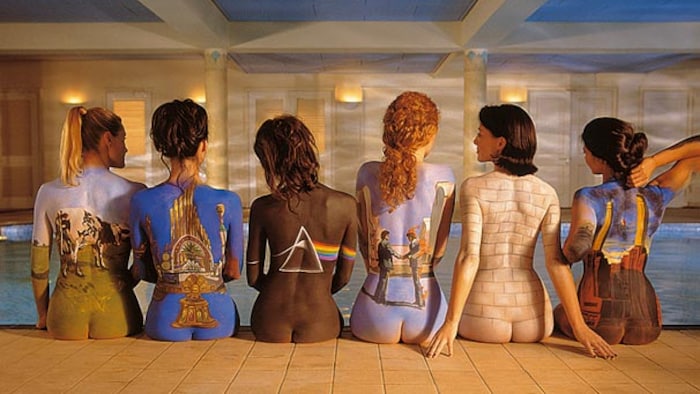 Six femmes vue de dos, assises sur le bord d'une piscine, chacune avec un album de Pink Floyd peint sur le dos. 