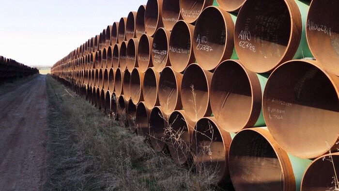 Des centaines de tuyaux de pipeline empilés à l'extérieur.