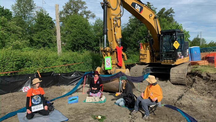 Des personnes qui font de la méditation devant un bulldozer.