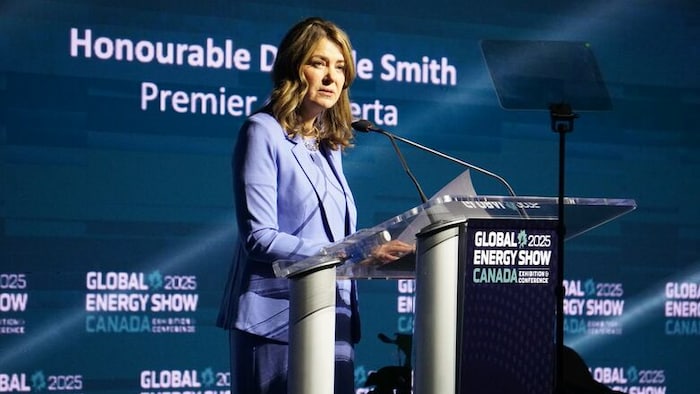 Danielle Smith est debout devant un podium et s'adresse à un micro.