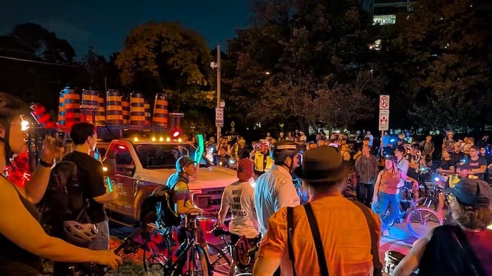 Des protestataires près d'un camion transportant des cônes à proximité de la piste cyclable de la rue Bloor Ouest à Toronto, le 13 octobre 2026.