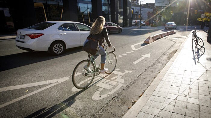 Une cycliste roule sur une piste cyclable au centre-ville de Toronto.