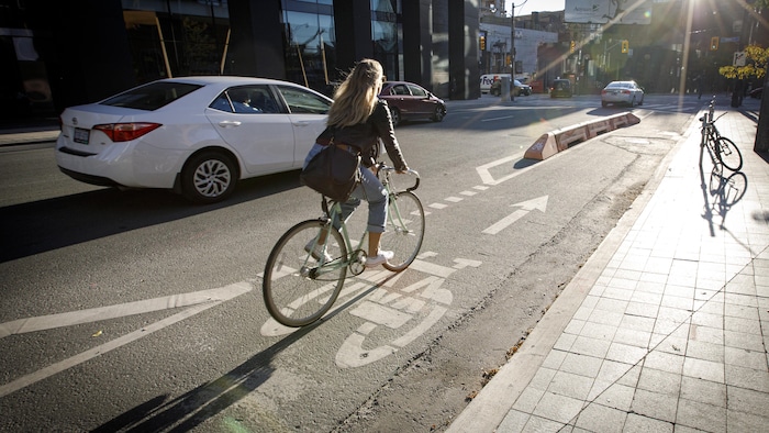 Des cyclistes traversent le centre-ville de Toronto sur une piste cyclable le 8 novembre 2021.