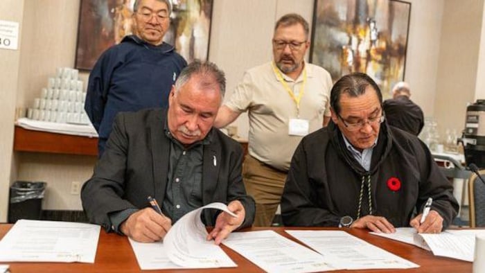 Les deux hommes signent des documents. 