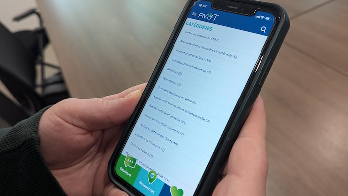 Alex Tremblay tient son téléphone dans les mains sur la page des catégories de l'application.