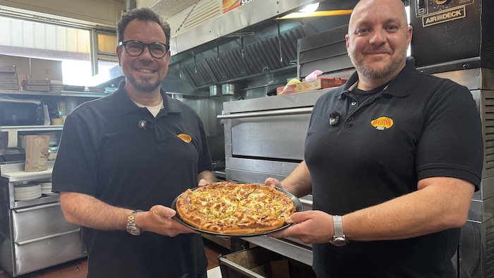 Jim Kolitsas et Spero Milios présentent fièrement une pizza réginoise, toute garnie.
