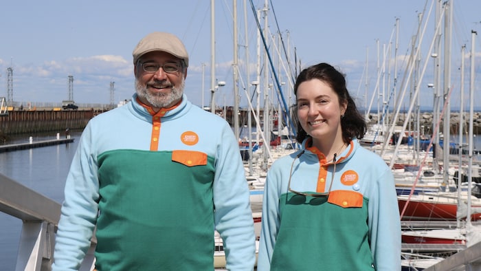 Deux agents de l'organisme Place aux jeunes devant une marina.