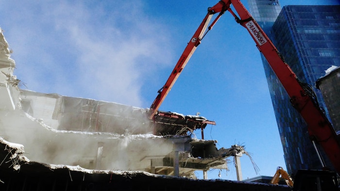 Une excavatrice détruit en morceaux la structure.