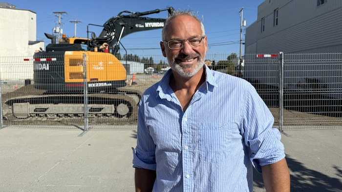 Sébastien D'Astous sourit à la caméra devant les travaux à la future place publique d'Amos.