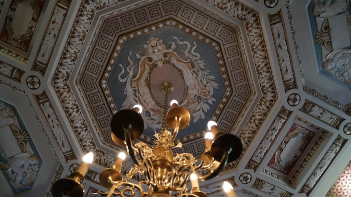 Un plafond richement décoré avec un chandelier.