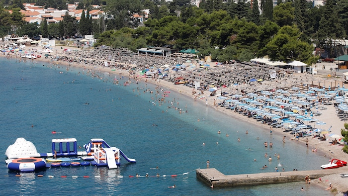 Des personnes profitent de la plage de Budva au Monténégro allongées sur des chaises longues sous des parasols, le 18 juillet 2023.