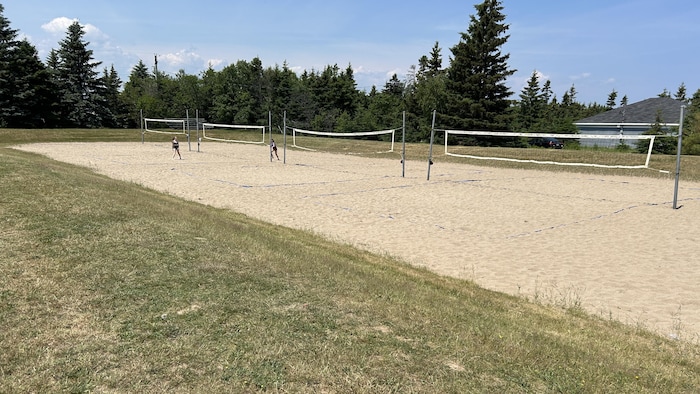Des terrains de volleyball de plage, deux personnes y jouent.
