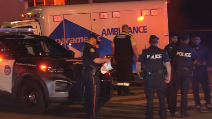 Des policiers devant une ambulance.
