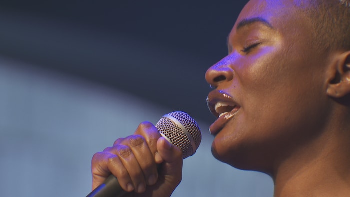 Une femme chante dans un micro.