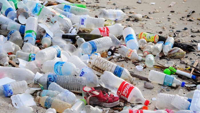 Des déchets et plusieurs bouteilles de plastique vides jonchent le sol d'une plage en Malaisie.