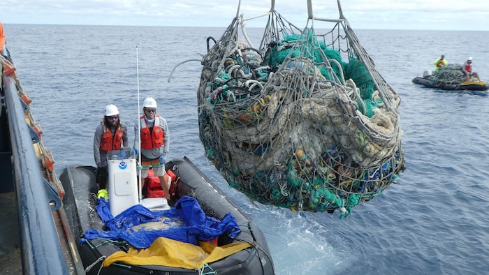 Une équipe en bateau retire des eaux des filets de pêche et des produits de plastique abandonnés près de l'atoll de Kure, à Hawaï.