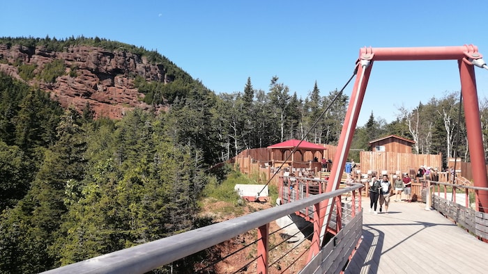 Des gens marchent sur une plateforme de bois à flanc de montagne.