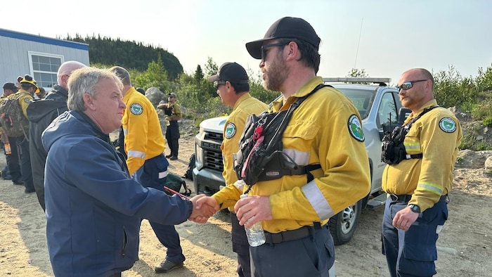 Le ministre serre la main d'un homme en uniforme jaune.