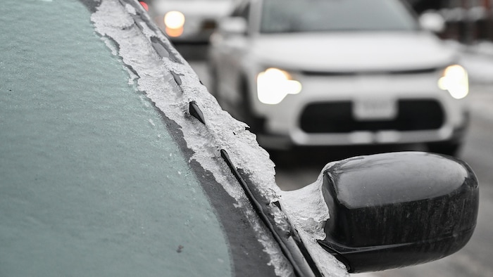 Du givre recouvre le pare-brise d'une voiture.