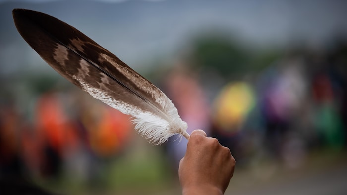 Une femme brandissant une plume d'aigle au passage d'un convoi de camionneurs, en soutien au peuple Tk'emlups te Secwepemc, après la découverte des restes d'enfants enterrés près de l'ancien pensionnat indien de Kamloops, en Colombie-Britannique.