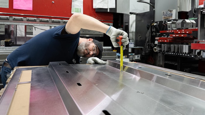 Networking among companies to deal with American prices star-news.press/wp A man measuring factory tape examines a sheet of metal.
