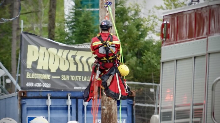 Un pompier accroché à des cordages se hisse dans les airs.