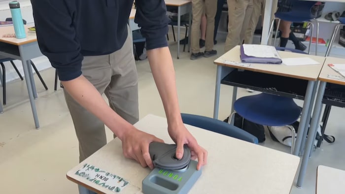 Un élève fait une démonstration pour montrer comment ouvrir une pochette avec un aimant puissant.