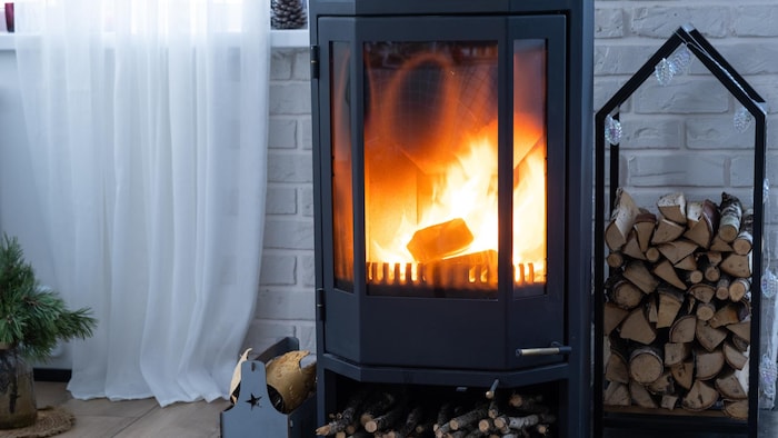Un poêle à bois aux allures contemporaines dans lequel un feu brûle.