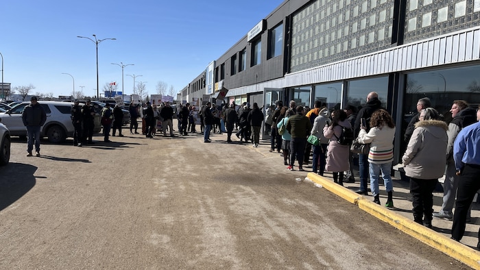 Des partisans font la file devant une poignée de manifestants. 