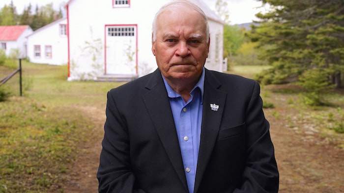 Le maire est debout devant la première chapelle du village.