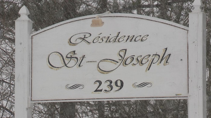 Une enseigne en bois peinte en blanc et vert que l'on retrouve en bordure de la route.
