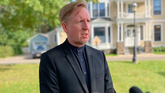Dominic Cardy en entrevue devant une grande maison.