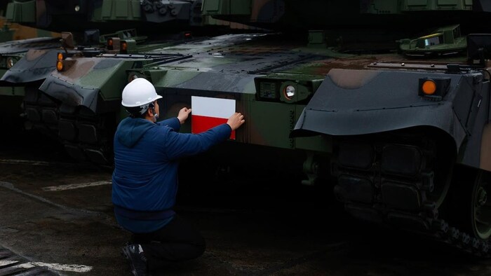 A worker puts a Polish flag on a South Korean Black Panther K2 tank in the Polish Navy port of Gdynia, Poland on Dec. 6, 2022.