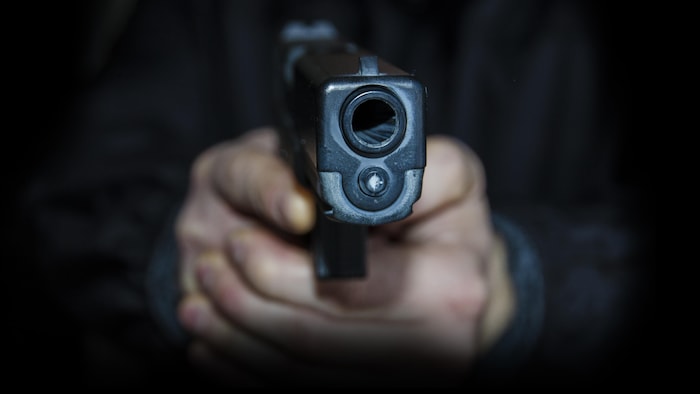 Une main tient un revolver.