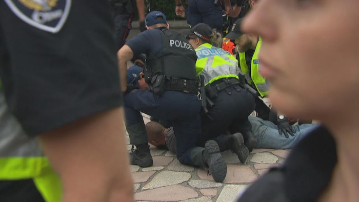 A person is pinned to the ground by police outside the National War Memorial. Ottawa police said they arrested four people after Thursday evening's speeches.