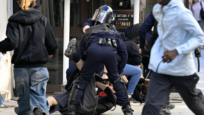 Des policiers plaquent un jeune au sol.