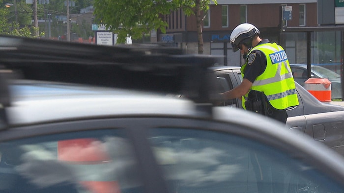 Un policier remet un constat d'infraction à un citoyen.