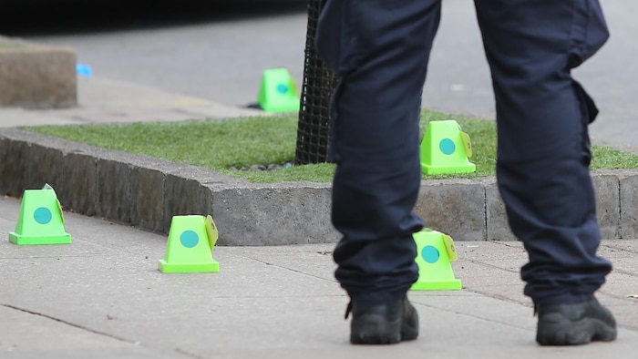 Des jambes d'un policier et des indices identifiés sur une scène de crime.