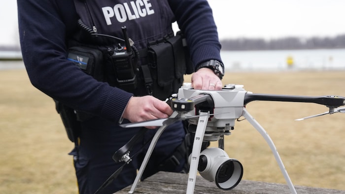 Un policier manipule un drone sur une table dans un parc.