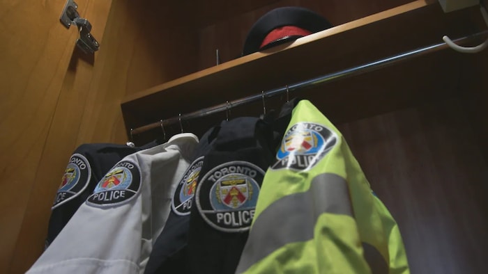 Des uniformes de police suspendus dans un placard.
