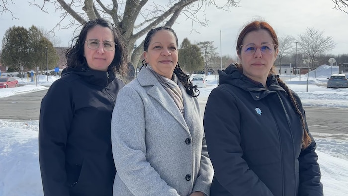 Les trois présidentes de syndicats se tiennent debout devant l’école secondaire Joseph-Hermas-Leclerc à Granby.
